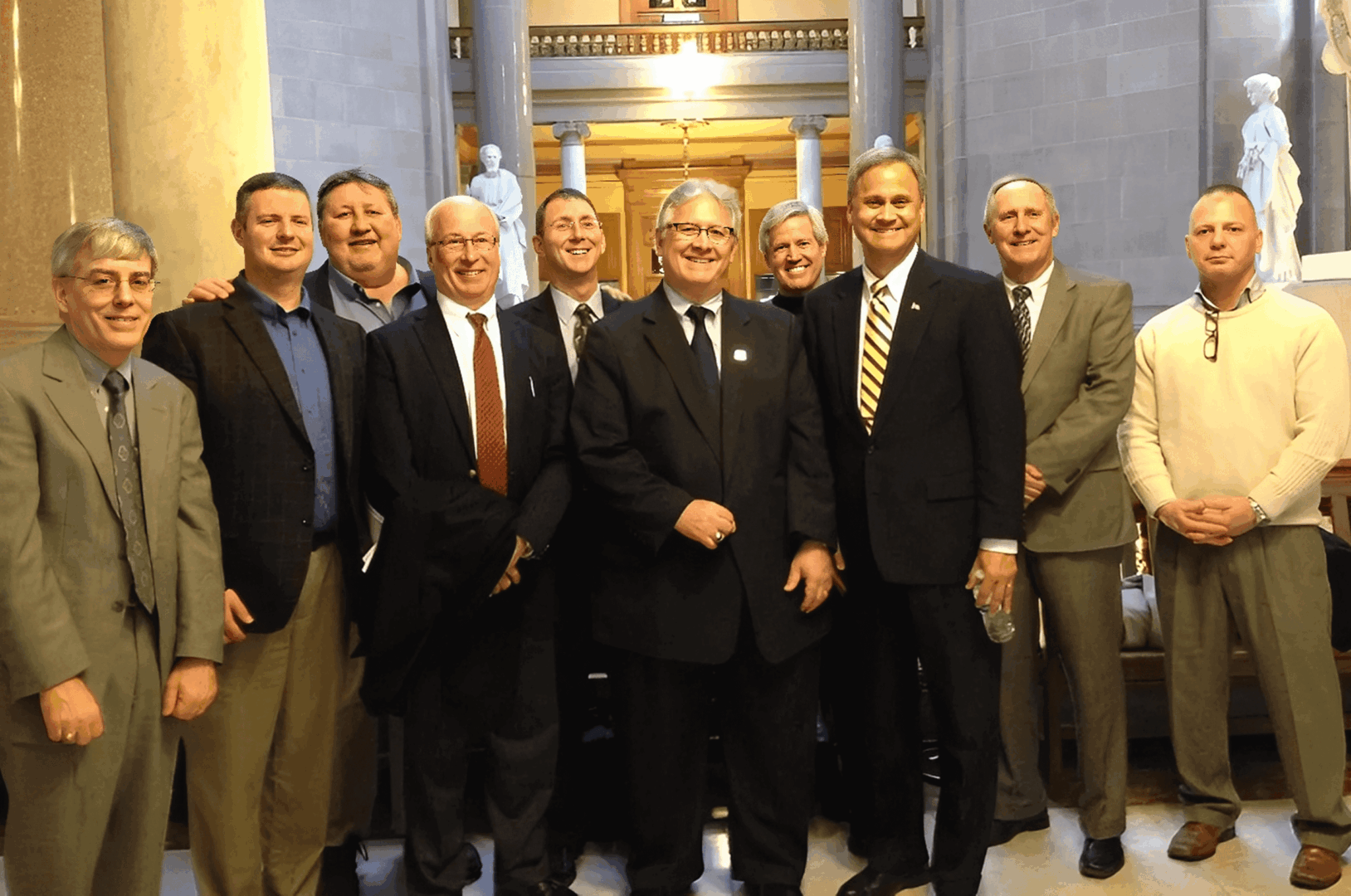 Group of men in suits, standing indoors.